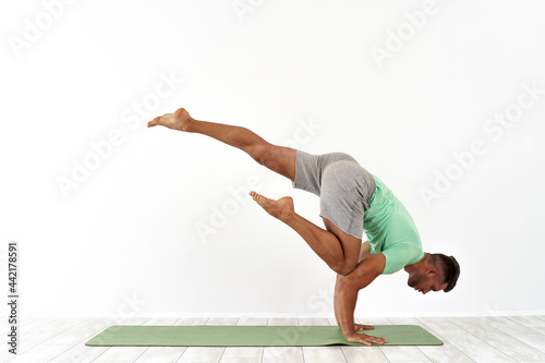 Fototapeta Naklejka Na Ścianę i Meble -  Man practicing balance yoga pose on white studio background