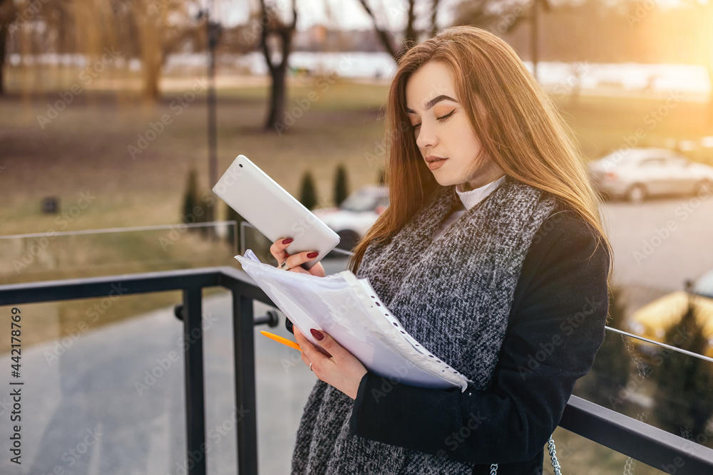 Fototapeta premium Woman sitting concrete stairs hold read use tablet pc documents contract resume for work. Lady looking for a job. Small busy business owner, copyspace. Freelancer make notes online studying 