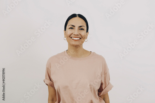Porträtt av glad kvinna med rosa t-shirt framför vit bakgrund
