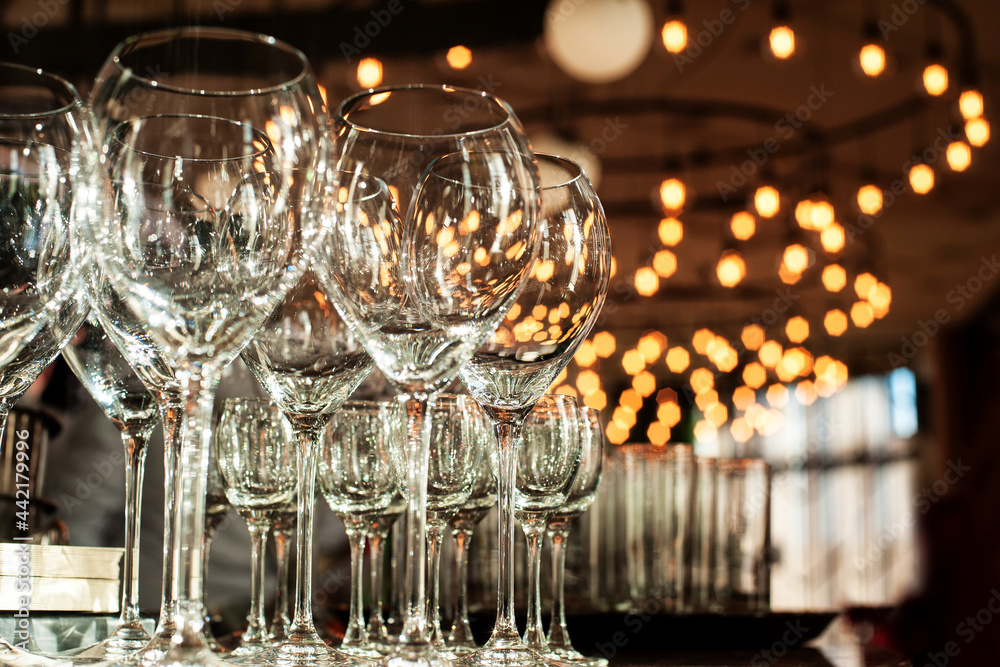 empty wine glasses on the background of bokeh from chandeliers in the restaurant empty wine glasses on the background of bokeh from chandeliers in the restaurant
