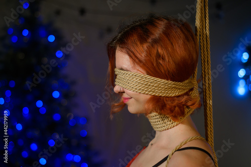 Girl in lace red underwear tied with ropes in Japanese shibari style at Christmas decorations. photo