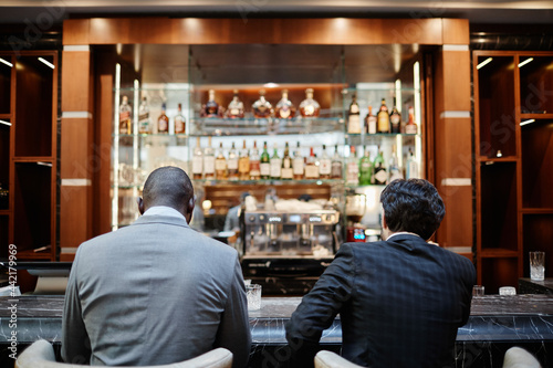 Back view portrait of two successful business people at bar in hotel lobby during business trip