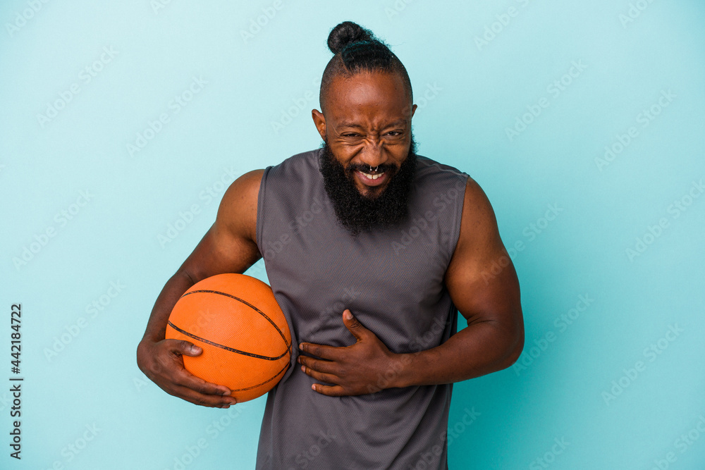 African american man playing basketball isolated on blue background laughing and having fun.