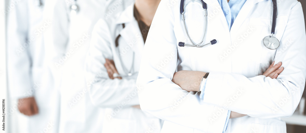 Group of modern doctors standing as a team with arms crossed in hospital office. Medical help, insurance in health care, best desease treatment and medicine concept Group of modern doctors standing as a team with arms crossed in hospital office. Medical help, insurance in health care, best desease treatment and medicine concept