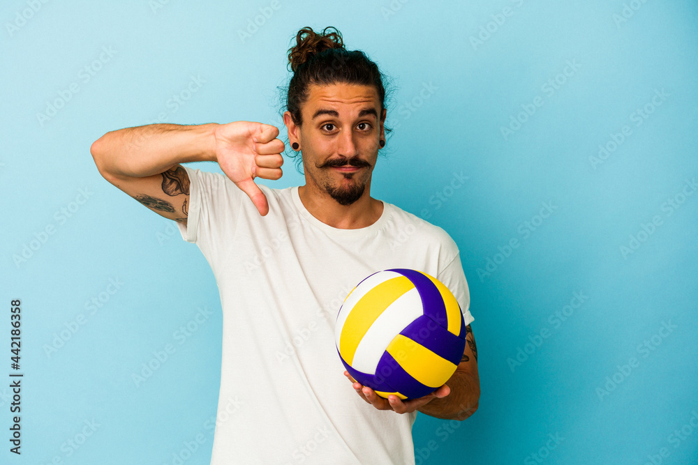 Young caucasian man with long hair isolated on blue background showing a dislike gesture, thumbs down. Disagreement concept.