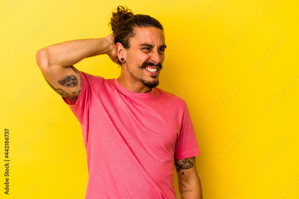 Young caucasian man with long hair isolated on yellow background suffering neck pain due to sedentary lifestyle. Young caucasian man with long hair isolated on yellow background suffering neck pain due to sedentary lifestyle.