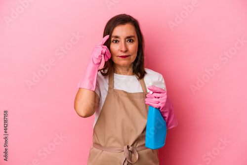 Middle age caucasian woman cleaning home isolated on pink background pointing temple with finger, thinking, focused on a task.