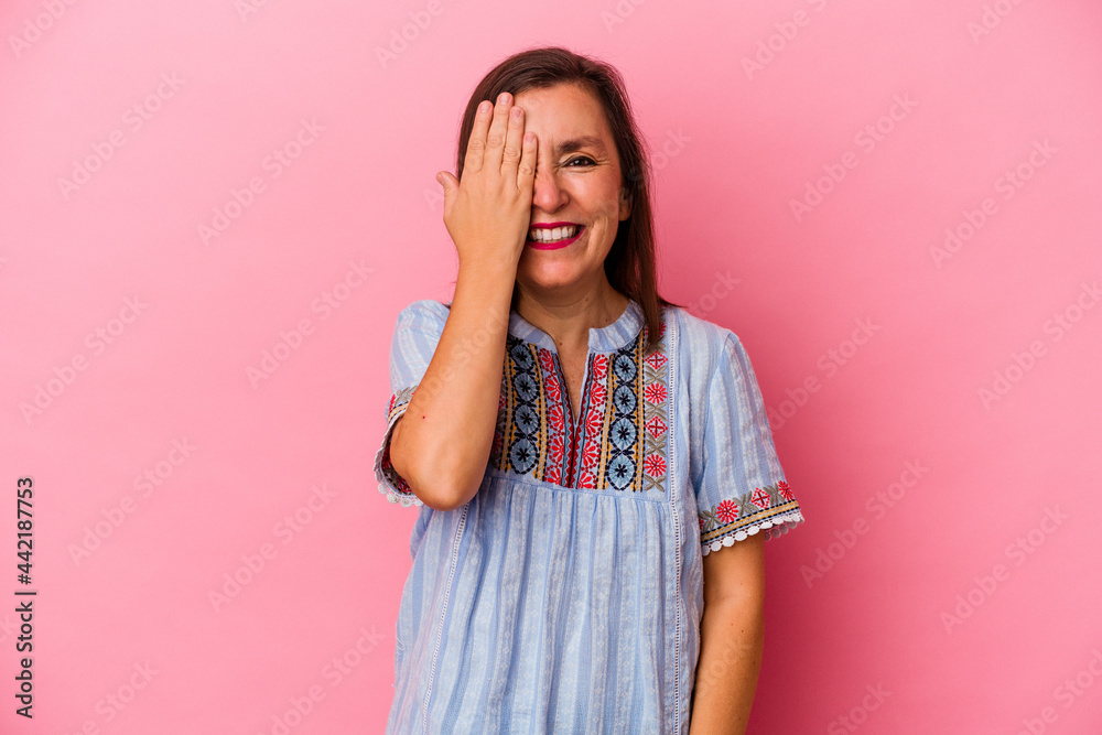 Middle age caucasian woman isolated on pink background having fun covering half of face with palm. Middle age caucasian woman isolated on pink background having fun covering half of face with palm.