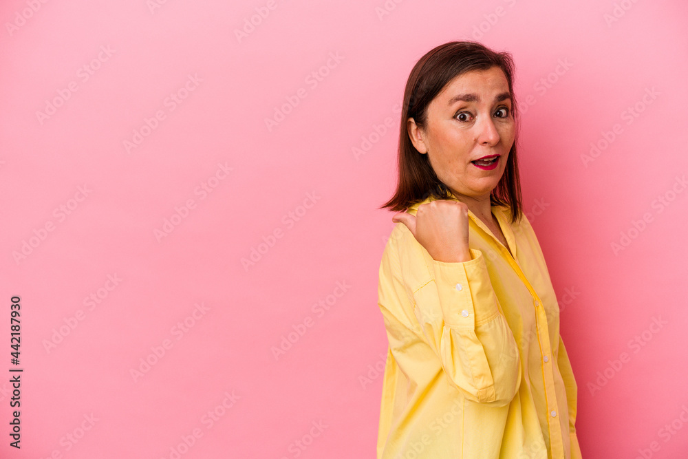 Middle age caucasian woman isolated on pink background points with thumb finger away, laughing and carefree. Middle age caucasian woman isolated on pink background points with thumb finger away, laughing and carefree.