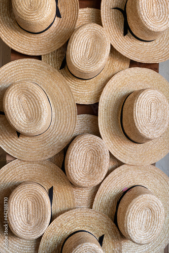 many straw Amish hats hanging on a wall