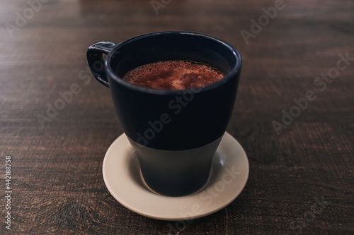 Closeup of hot cocoa drink in blue mug on dark wooden table.