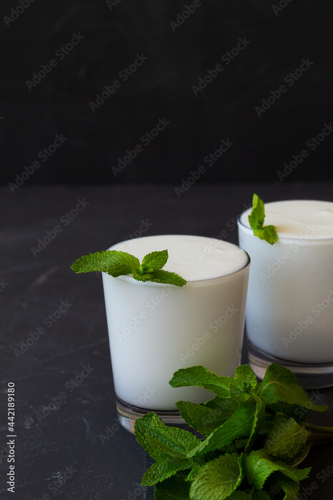 fresh yogurt with mint.Lassi drink with fresh green mint. cold dairy. Indian cuisine. copy space. ayran, milk with probiotics on the dark table. healthy, fermented products concept. vertical