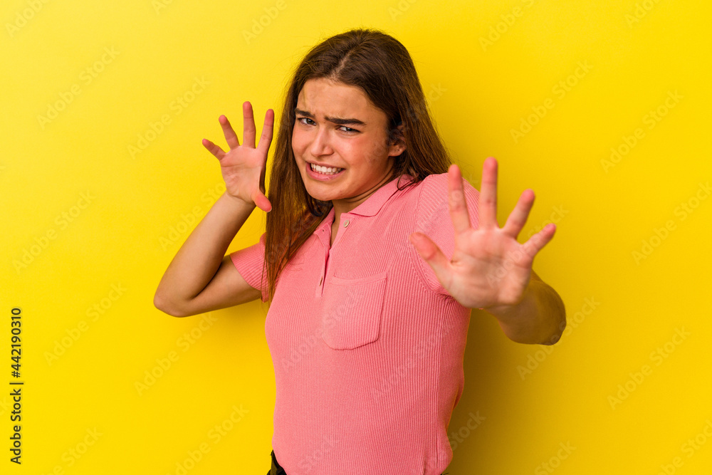 Young caucasian woman isolated on yellow background upset screaming with tense hands. Young caucasian woman isolated on yellow background upset screaming with tense hands.