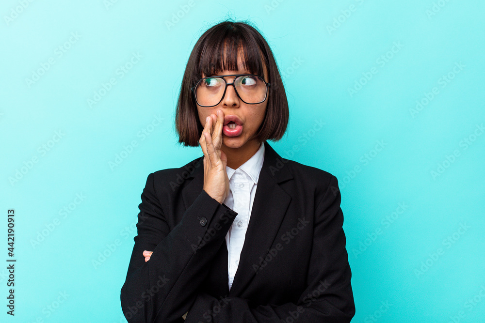 Young business mixed race woman isolated on blue background is saying a secret hot braking news and looking aside Young business mixed race woman isolated on blue background is saying a secret hot braking news and looking aside