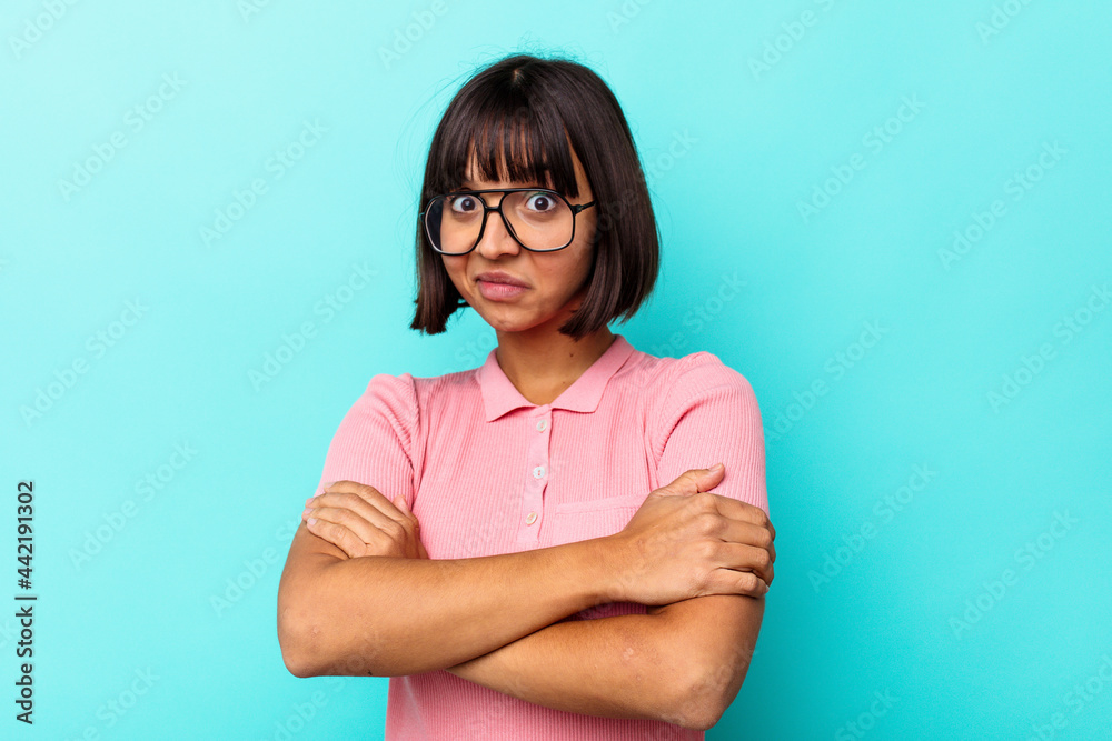 Young mixed race woman isolated on blue background hugs, smiling carefree and happy.