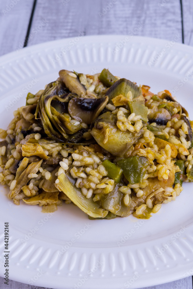 Close up view of rice paella with vegetables on wooden table