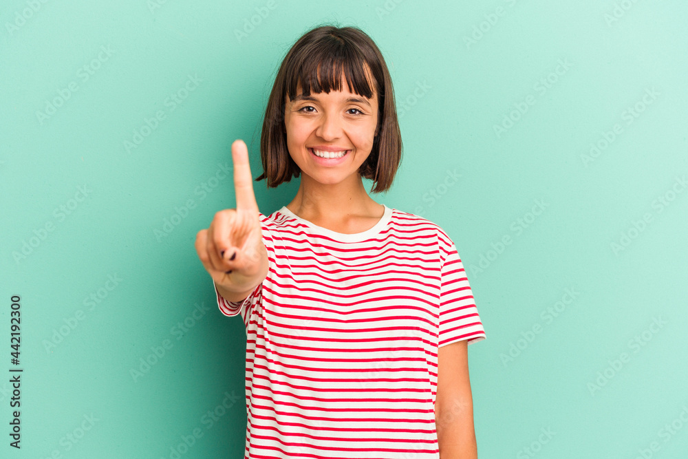 Young mixed race woman isolated on blue showing number one with finger. Young mixed race woman isolated on blue showing number one with finger.