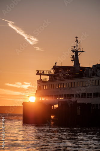 A sunset with orange sky and the silhouette of a ferry boat