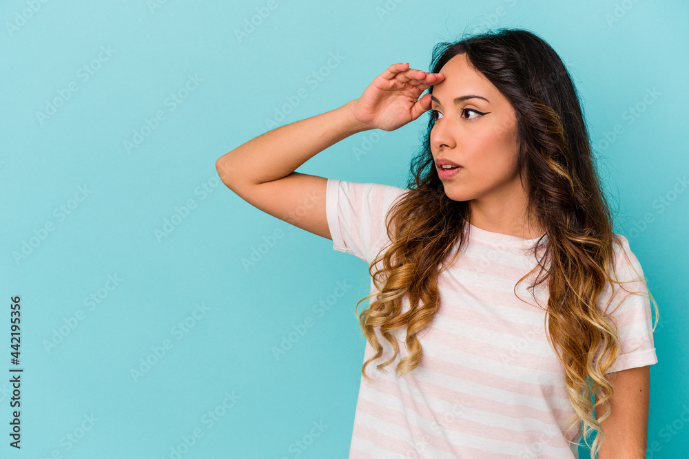 Young mexican woman isolated on blue background looking far away keeping hand on forehead. Young mexican woman isolated on blue background looking far away keeping hand on forehead.