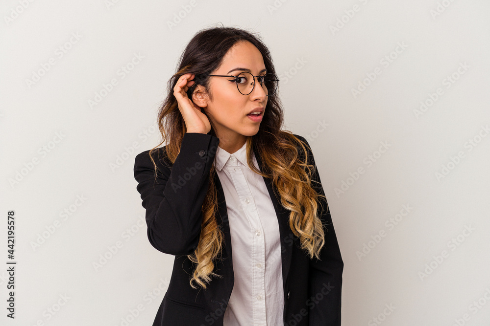 Young mexican business woman isolated on white background trying to listening a gossip.