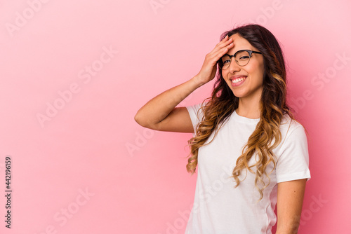 Young mexican woman isolated on pink background laughing happy, carefree, natural emotion.