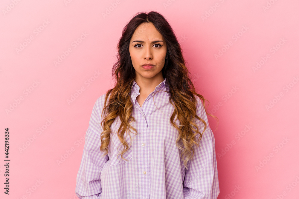Young mexican woman isolated on pink background sad, serious face, feeling miserable and displeased.