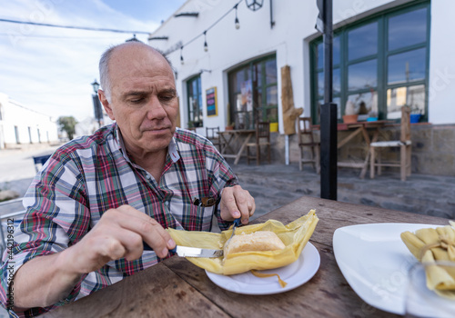 Hispanic senior man eating typical Argentine food
