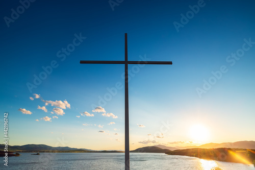 Christian cross against clouds and lake