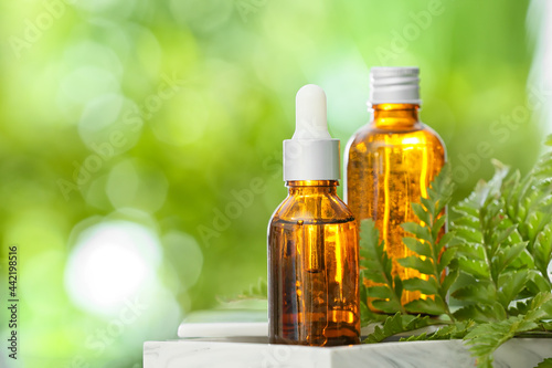 Fototapeta Naklejka Na Ścianę i Meble -  Bottles of essential oil on table outdoors, closeup