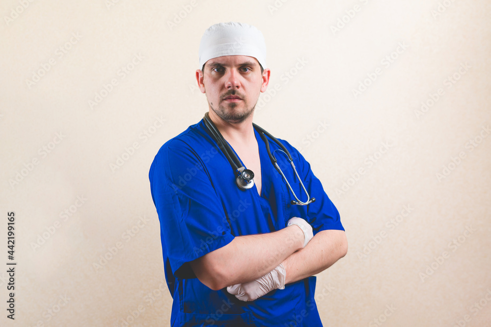 Young doctor portrait in blue suit with stethoscope and with his hands on his chest isolated on smooth background Young doctor portrait in blue suit with stethoscope and with his hands on his chest isolated on smooth background