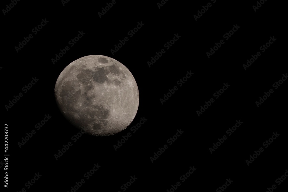 A close up portrait of the moon surrounded by the darkness and emptiness of space. The craters and other details of the only natural satellite of earth are clearly visible.