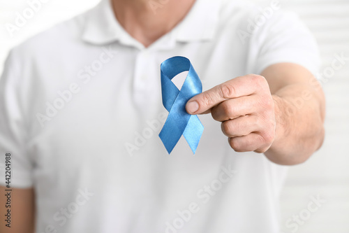 Fotografie Man with blue ribbon on light background, closeup