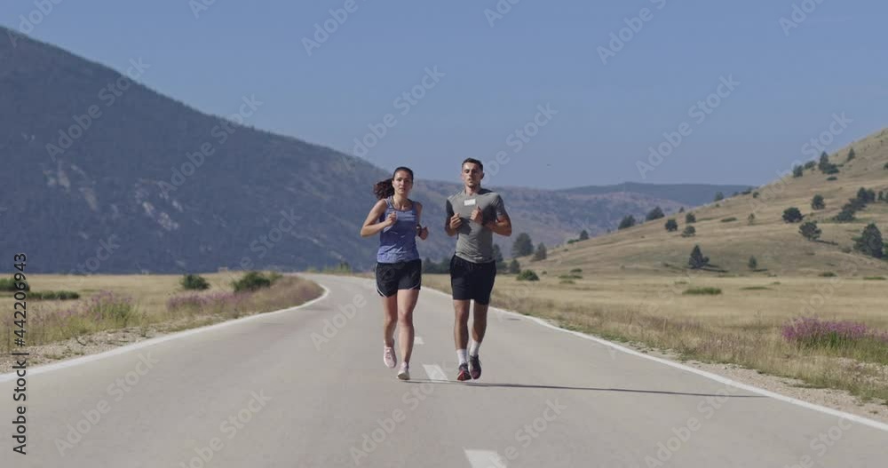 Tracking slow motion shot of sportive couple jogging outdoors in the morning, trail running experience in nature. Healthy lifestyle concept. Tracking slow motion shot of sportive couple jogging outdoors in the morning, trail running experience in nature. Healthy lifestyle concept.