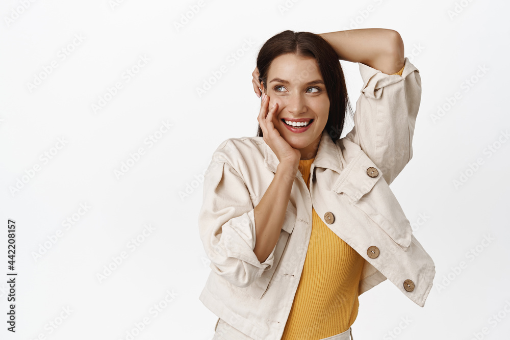 Tender and feminine brunette woman, laughing coquettish, smiling white teeth, touching her hair and cheeks, blushing coy, looking at upper left corner sale banner, white background Tender and feminine brunette woman, laughing coquettish, smiling white teeth, touching her hair and cheeks, blushing coy, looking at upper left corner sale banner, white background