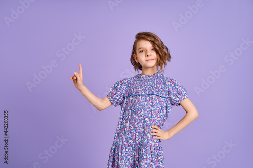 Look There. Excited Caucasian Kid Girl Pointing Thumb At Free Space For Text Posing On Purple Studio Background. Panorama