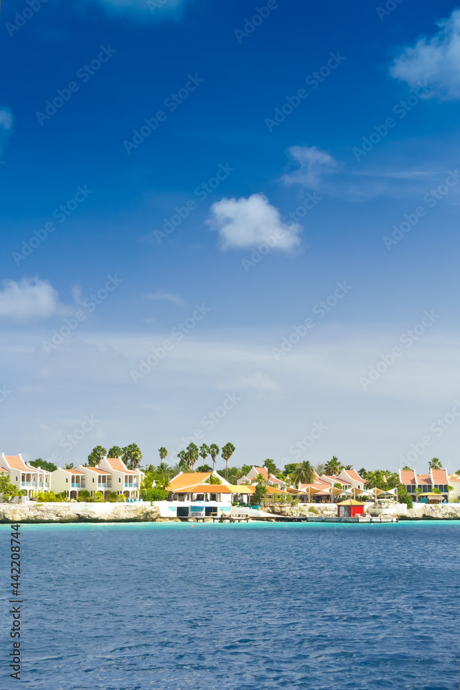 Resort hotel at the waterfront in Kraledijk, Bonaire, Dutch Antilles, Caribbean Sea, with emerald seashore and blue sky
