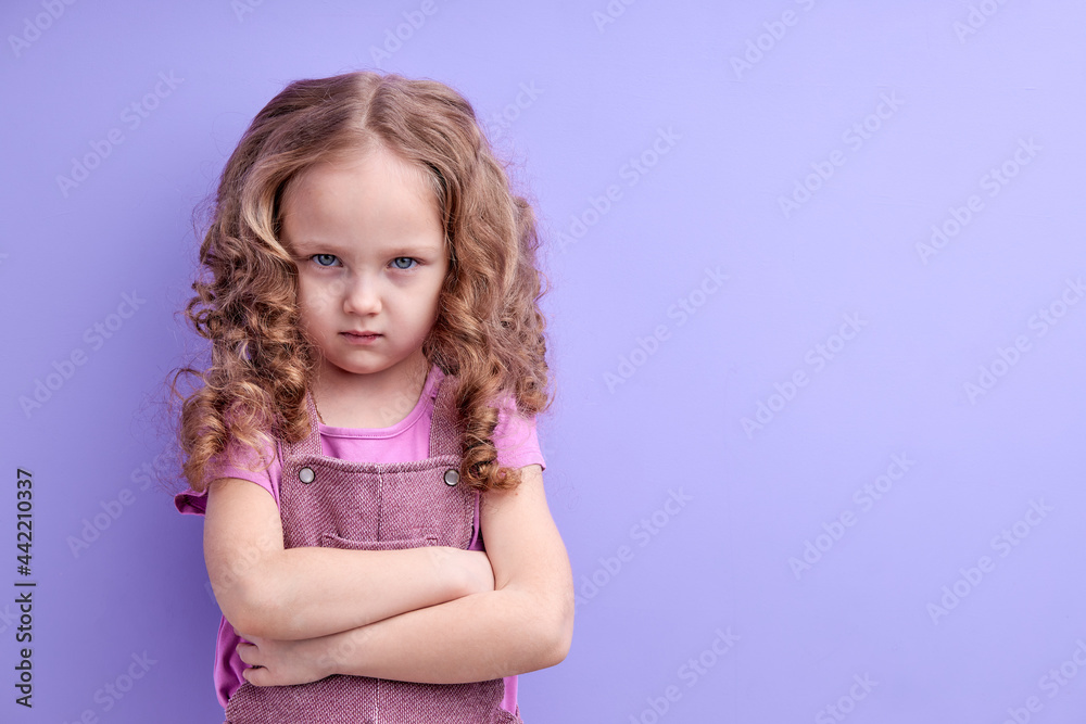 Upset little kid girl looking unhappy at camera, tired upset preschool child is offended, with thoughtful face, crossed hands, melancholic or bored, isolated over purple studio background Upset little kid girl looking unhappy at camera, tired upset preschool child is offended, with thoughtful face, crossed hands, melancholic or bored, isolated over purple studio background