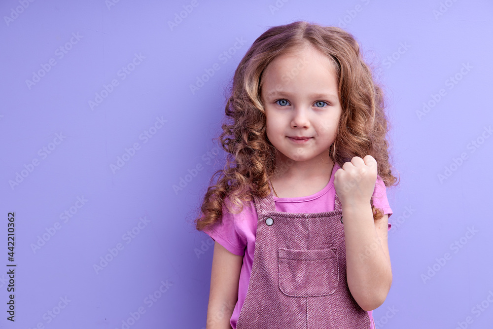 Portrait of emotional angry child girl showing fist, threatens you, poses indoor. Furious child gestures indoor. Childhood concept. copy space Portrait of emotional angry child girl showing fist, threatens you, poses indoor. Furious child gestures indoor. Childhood concept. copy space