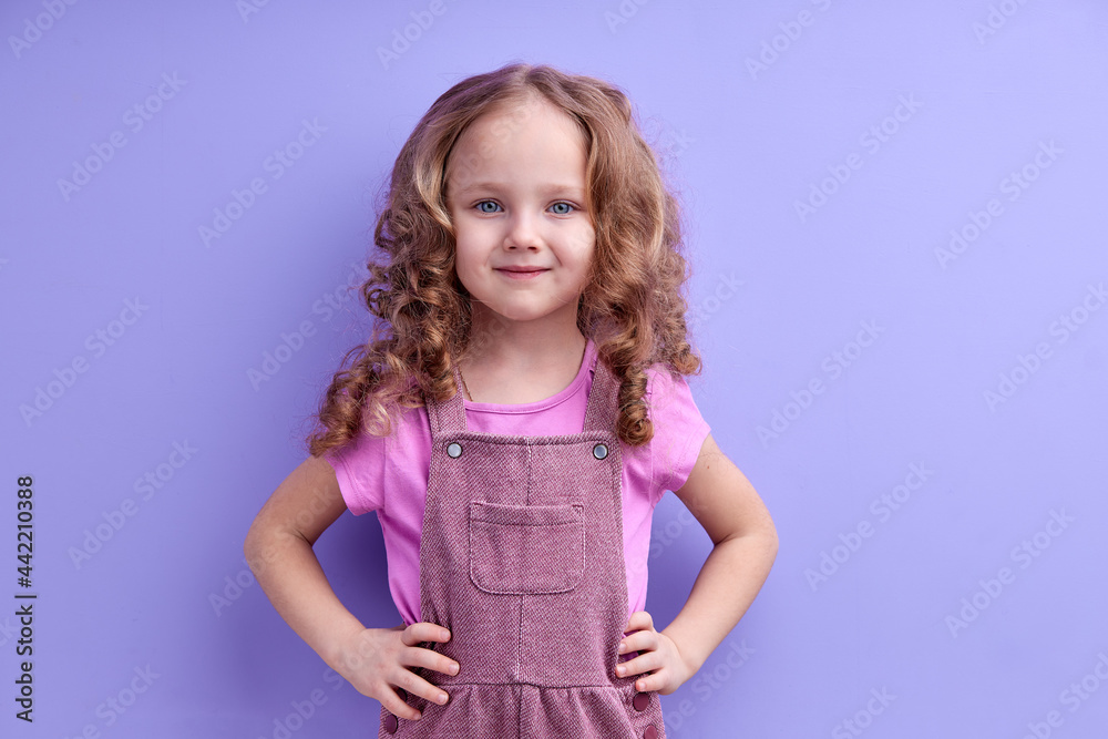 Caucasian Smiling Child Girl Isolated On Purple Background, Look At Camera, Posing, In Casual Outfit. Children, People Lifestyle Concept Caucasian Smiling Child Girl Isolated On Purple Background, Look At Camera, Posing, In Casual Outfit. Children, People Lifestyle Concept