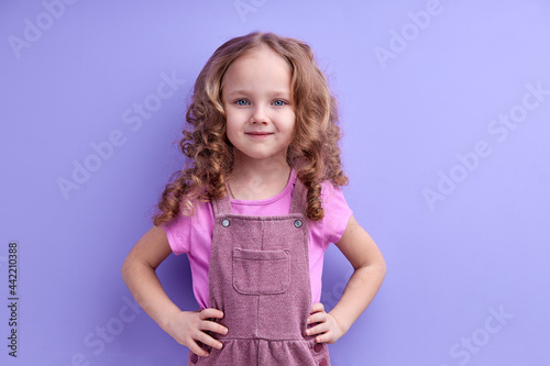 Caucasian Smiling Child Girl Isolated On Purple Background, Look At Camera, Posing, In Casual Outfit. Children, People Lifestyle Concept