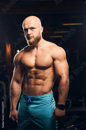 Handsome muscular man standing shirtless at the gym
