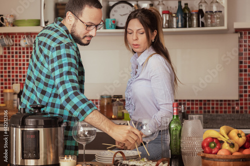 pareja joven acomoda la comida en la cocina de su casa mientras esperan invitados a comer