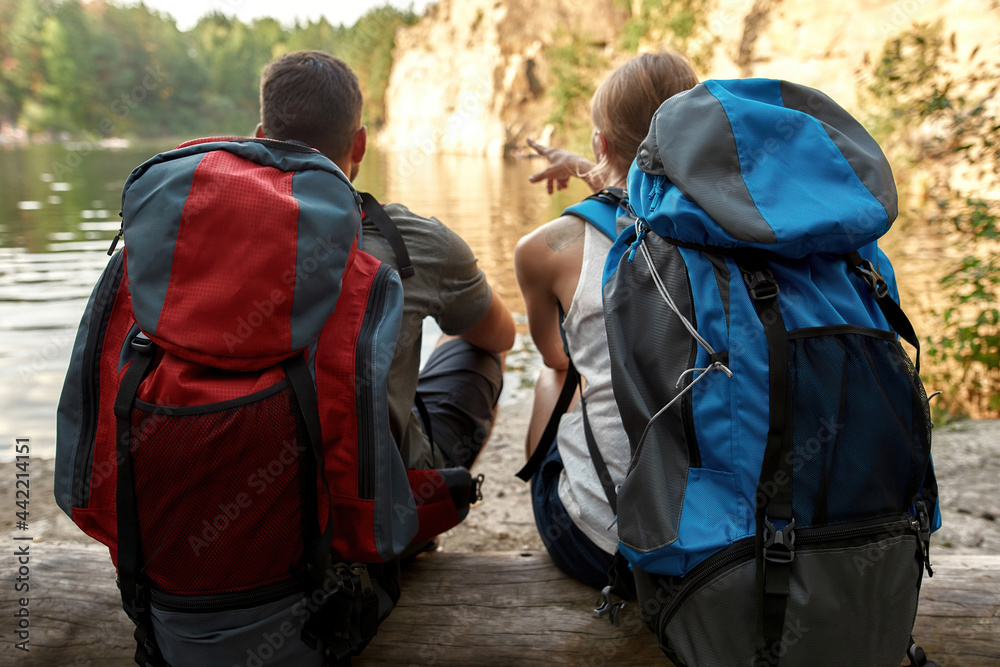 Young caucasian pair with large backpacks on log