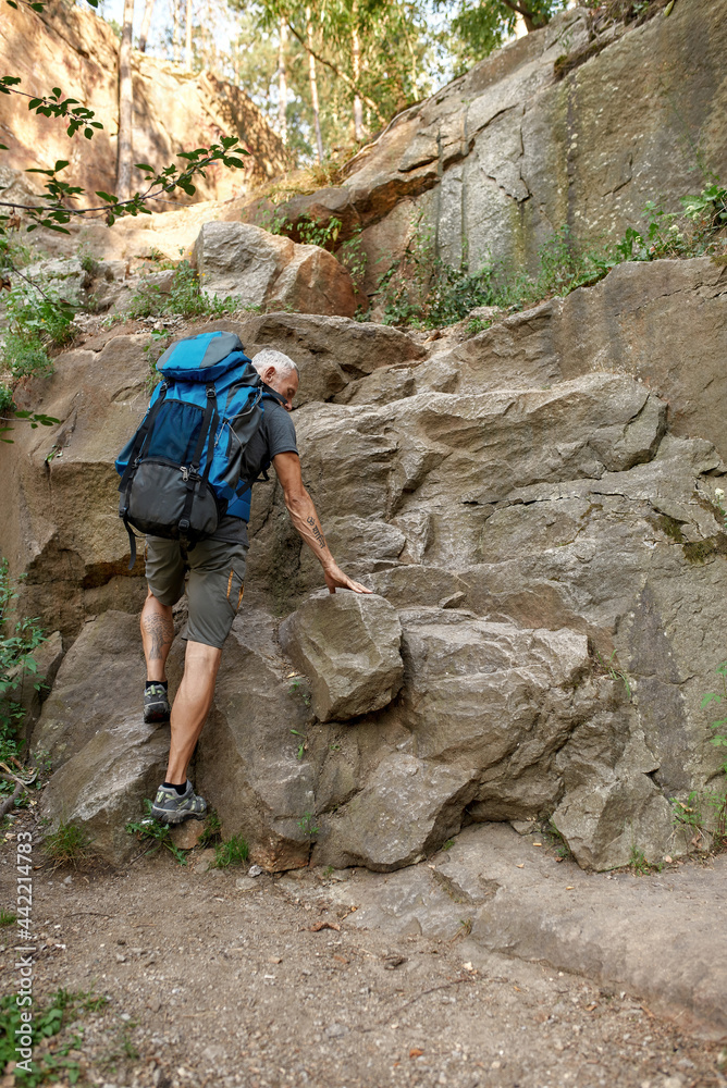 Rear view of middle aged caucasian man climbing rocks