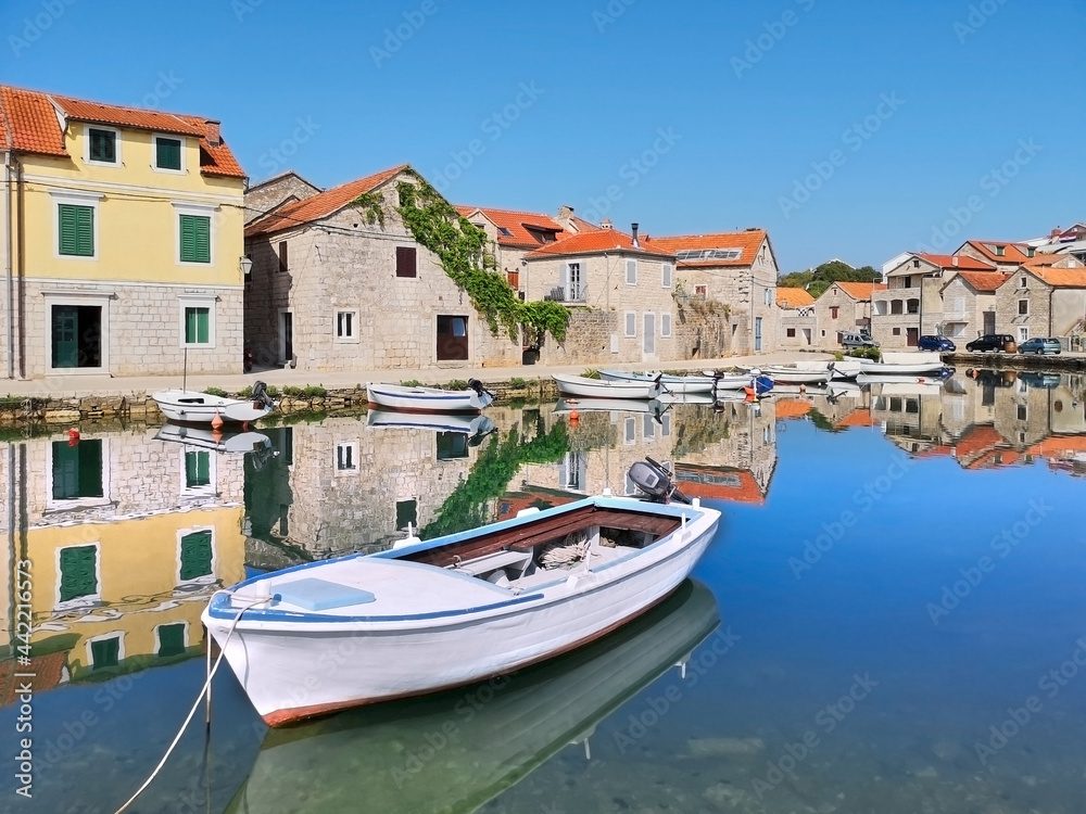 Old historic houses in Vrboska village, Hvar island, Dalmatia, Croatia, Europe. Fisherman boat with reflection. Travel and vacation destination. Old fisherman village, popular among tourists.