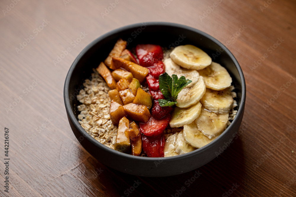 Vegetarian breakfast in a cafe: oatmeal with honey, caramelized bananas and apples, very beautiful appetizing shot