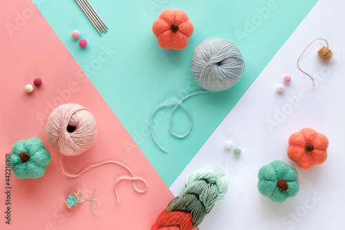 Various wool yarn and knitting needles, creative knitting hobby. Panoramic background in pink, mint green, white. Pastel color hobby arrangement on layered paper background.