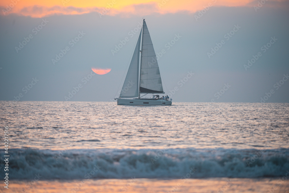 Yacht sailing against sunset. Landscape with skyline sailboat and sunset silhouette. Yachting tourism. Romantic trip on luxury yacht during the sea sunset. Ocean seascape.
