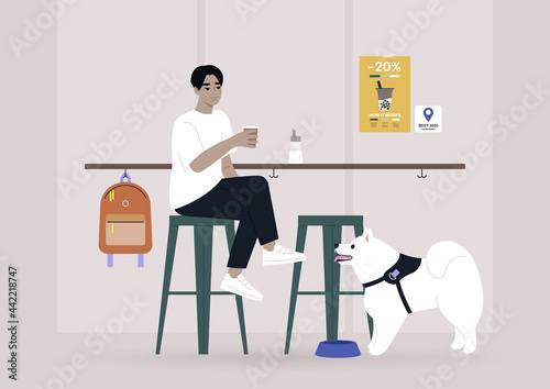 Young male Asian character drinking coffee at the bar counter of a dog-friendly place, modern lifestyle