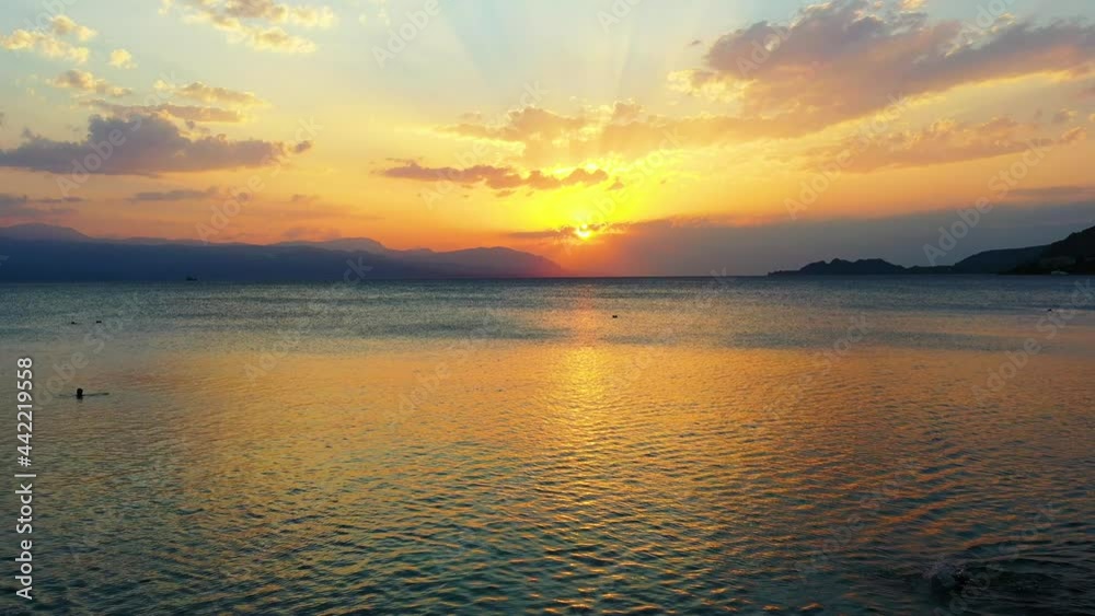 Aerial of a very beautiful sunset in Loutraki, Greece. The drone fly over people swimming in the sea, and towards the beautiful sunset. It is a beautiful summer evening. Drone aerial 4K Aerial of a very beautiful sunset in Loutraki, Greece. The drone fly over people swimming in the sea, and towards the beautiful sunset. It is a beautiful summer evening. Drone aerial 4K